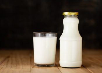 Glass of milk and a bottle of fresh milk on a black background